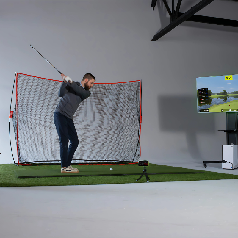 Man practicing golf swing in a room with a screen displaying a golf course.