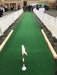 Green indoor putting green with a white flag at a convention center.