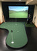Indoor putting green with golf bag and clubs against a scenic wall backdrop