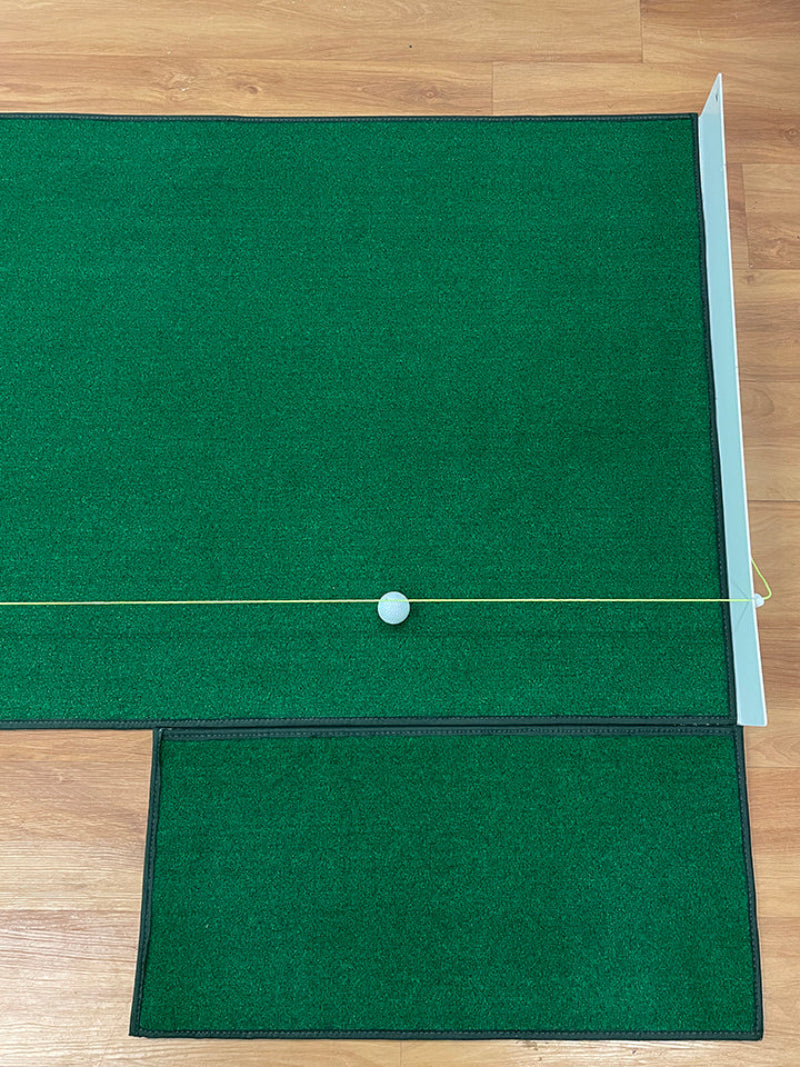 Green golf mat with a white ball on a wooden floor