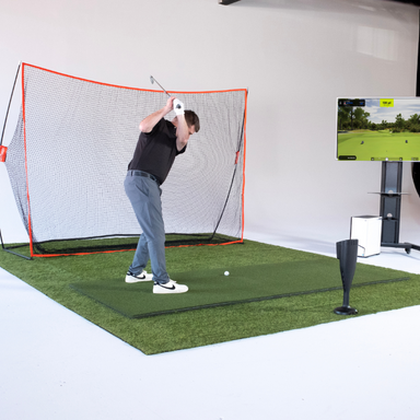 Person practicing golf swings in a home indoor golf simulator setup.