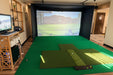Indoor golf simulator setup with Pure Flight Hitting Mat  and screen displaying a golf course.