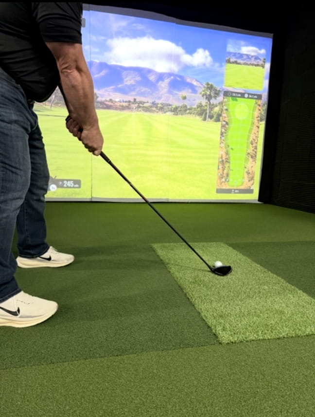 Person playing golf on a simulator using Big Moss Pure Flight Hitting Mat