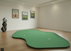 Green indoor putting green mat with holes on a wooden floor.