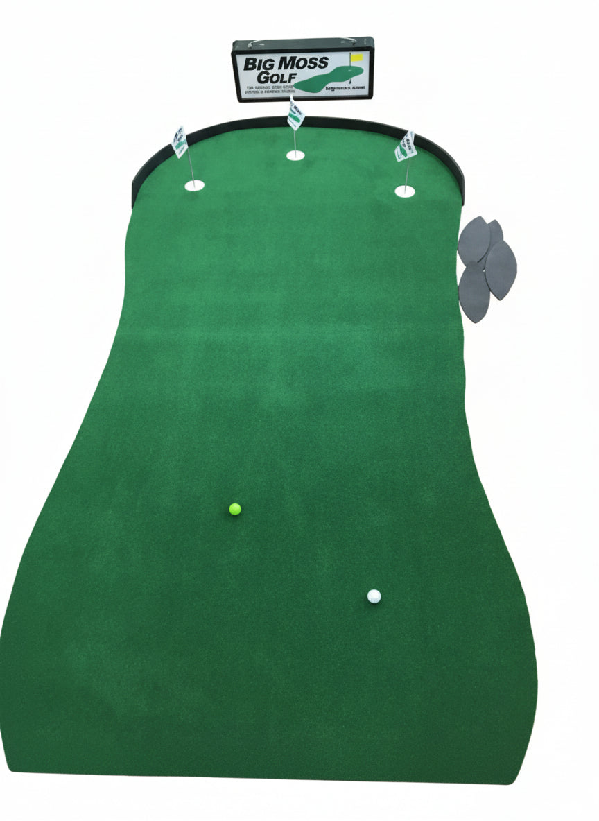 Indoor putting green with golf balls and markers on a wooden floor, featuring Big Moss Golf branding.