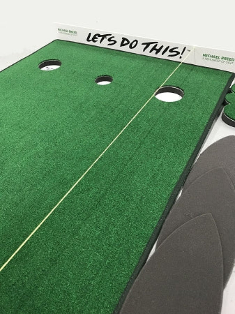 Green putting green mat with holes and 'Let's Do This!' text, featuring a golf club.