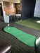 Indoor putting green with simulator screen and club holder in a room.